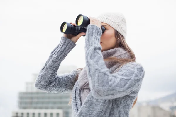 Hübsche Frau mit Winterkleidung beim Blick durchs Fernglas — Stockfoto