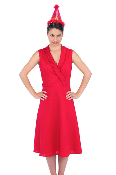 Ernste wunderschöne Brünette im roten Kleid mit Party-Hut — Stockfoto