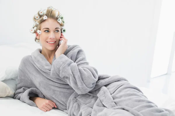 Gai détendu blonde femme dans cheveux bigoudis appelant avec son téléphone mobile — Photo