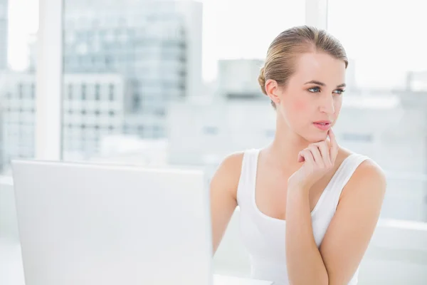 Nachdenkliche Blondine mit ihrem Laptop — Stockfoto