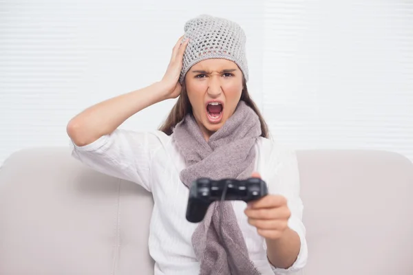 Boos brunette met winter hoed op het spelen van videospellen — Stockfoto