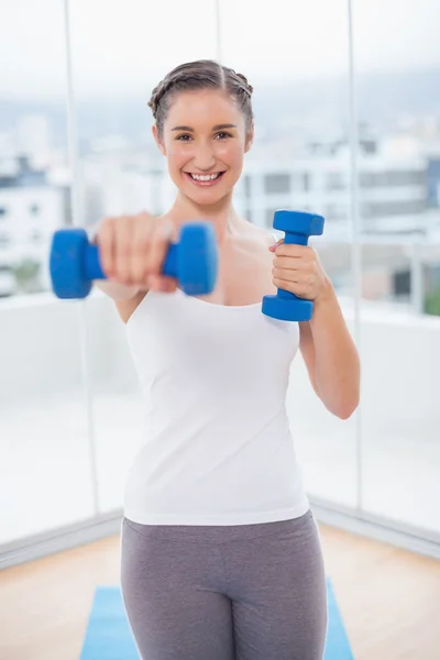 Sonriente atlética morena haciendo ejercicio con mancuernas — Foto de Stock