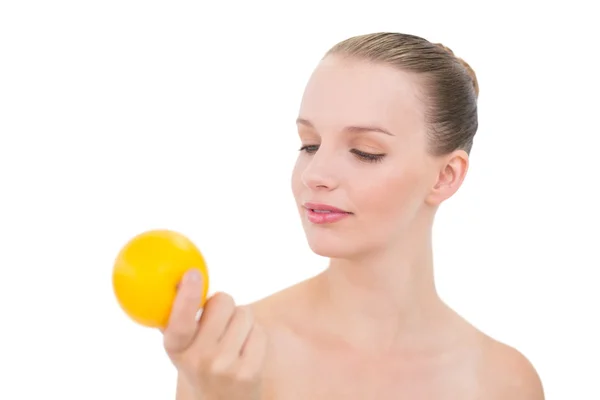 Pensive pretty blonde model looking at an orange — Stock Photo, Image