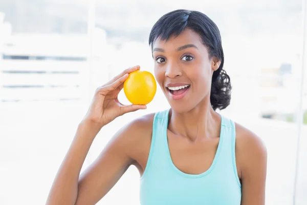 Überraschte schwarzhaarige Frau mit einer Orange — Stockfoto