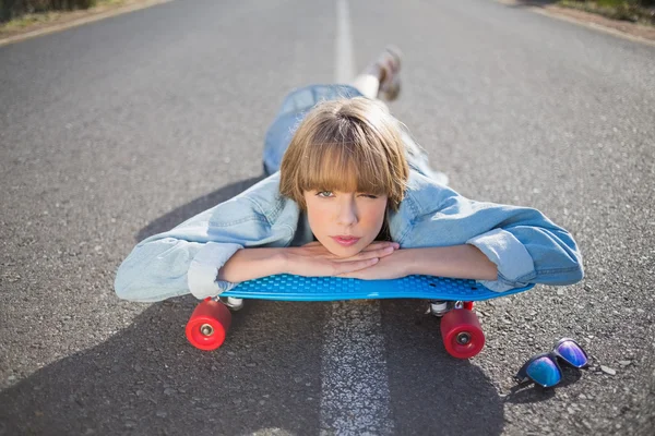 Весела молода блондинка лежить на дорозі підморгує на камеру — стокове фото