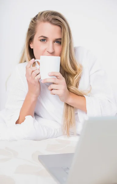 Smiling pretty model drinking coffee lying on cosy bed — Stock Photo, Image