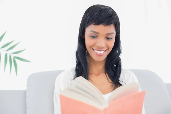 Thoughtful black haired woman in white clothes reading a book — Stock Photo, Image
