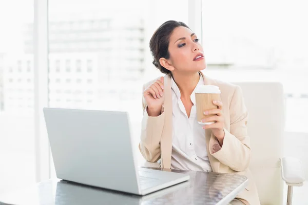 Kobieta myśli picia kawy podczas pracy na laptopie — Zdjęcie stockowe