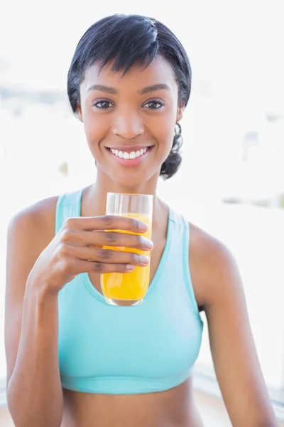 Mujer alegre en forma bebiendo un vaso de jugo de naranja —  Fotos de Stock