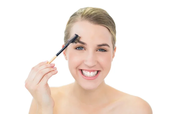 Sonriente rubia atractiva usando cepillo de cejas — Foto de Stock