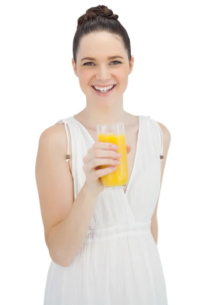 Modelo alegre en vestido blanco sosteniendo vaso de jugo de naranja —  Fotos de Stock