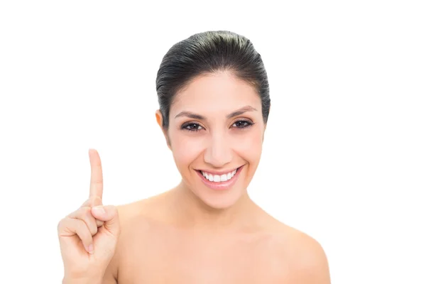 Smiling brunette pointing up with one hand — Stock Photo, Image