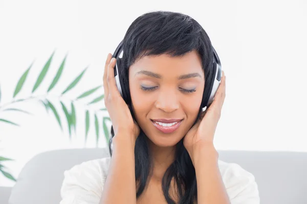 Femme aux cheveux noirs rêveuse en vêtements blancs écoutant de la musique — Photo