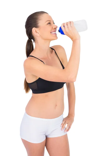 Smiling toned woman in sportswear drinking water — Stock Photo, Image