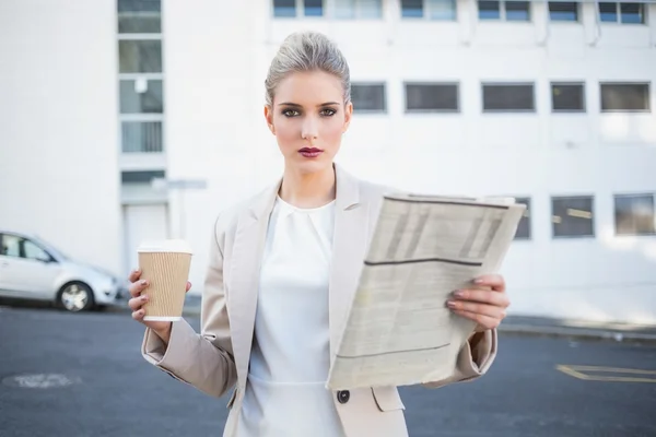 Serious stylish businesswoman holding newspaper and coffee — Stock Photo, Image