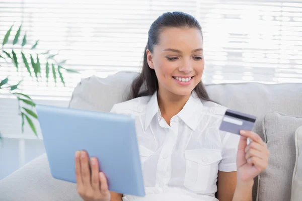 Счастливая милая женщина, покупающая онлайн с помощью своего планшетного компьютера — стоковое фото