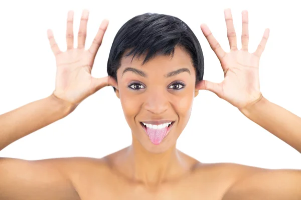 Mujer de pelo negro alegre posando con la lengua hacia fuera y las manos alrededor de su cabeza —  Fotos de Stock