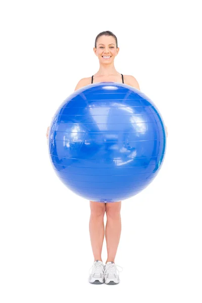 Sonriente mujer en forma sosteniendo la pelota de ejercicio delante de ella — Foto de Stock