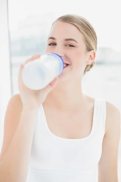 Счастливая спортивная женщина пьет воду из своей фляжки — стоковое фото