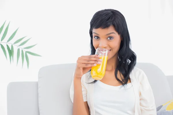 Charmante schwarzhaarige Frau in weißer Kleidung, die Orangensaft trinkt — Stockfoto