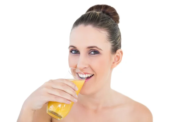 Woman drinking orange juice looking at camera — Stock Photo, Image