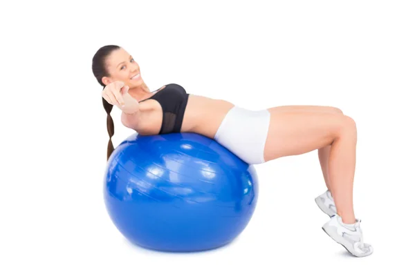 Smiling sporty woman working out with exercise ball pointing at camera — Stock Photo, Image