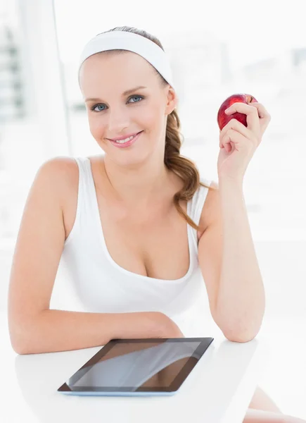 Cheerful pretty sportswoman holding an apple — Stock Photo, Image