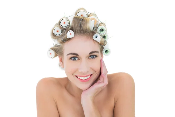 Cheerful blonde model in hair curlers holding her head — Stock Photo, Image