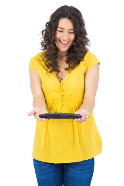 Smiling casual young woman holding remote — Stock Photo, Image