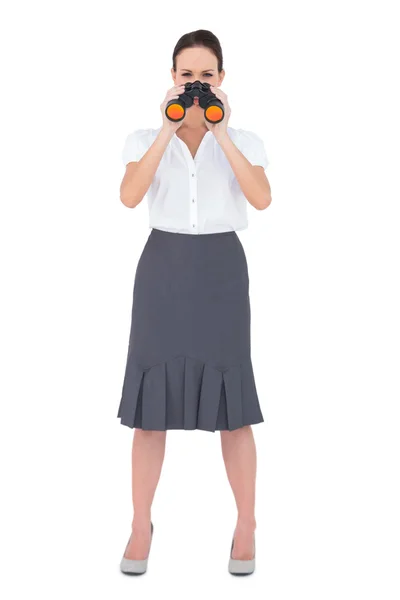 Curious elegant businesswoman holding binoculars — Stock Photo, Image