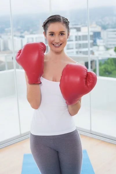 Lächelnde sportliche Brünette mit roten Boxhandschuhen — Stockfoto