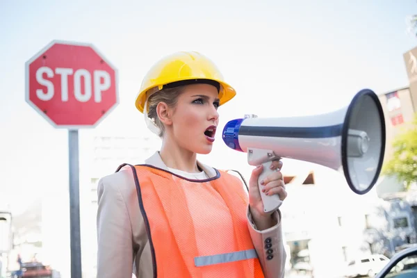 Businesswoman wearing builders clothes shouting in megaphone — Stock Photo, Image