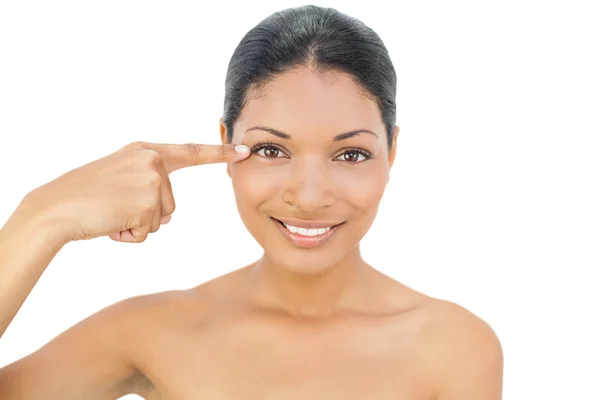Smiling black haired model pointing at her eye — Stock Photo, Image