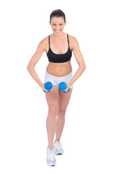 Happy sporty brunette exercising with dumbbells — Stock Photo, Image