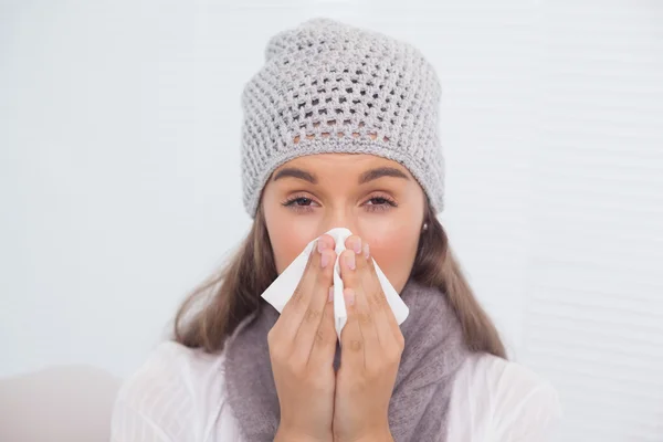 Morena doente com chapéu de inverno em soprar o nariz — Fotografia de Stock