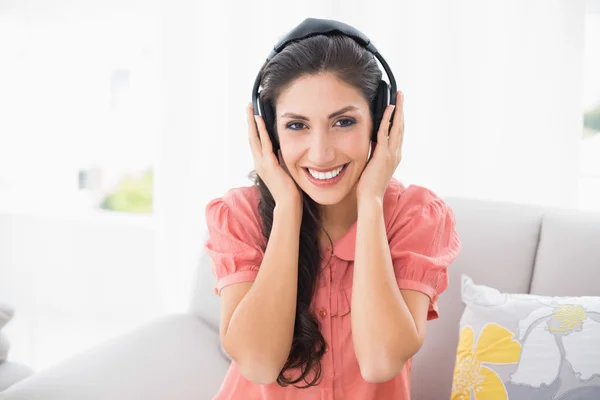 Morena feliz sentada en su sofá escuchando música —  Fotos de Stock