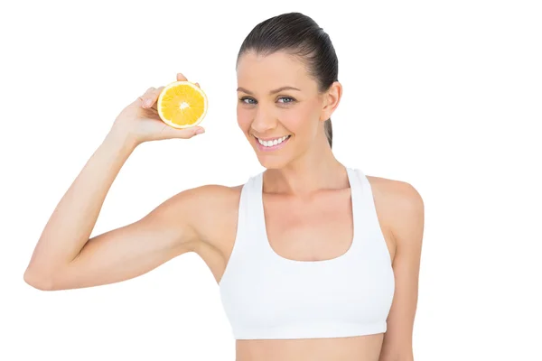 Счастливая женщина в спортивной одежде держит кусочек апельсина — стоковое фото