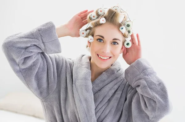 Gülümseyen rahatlamış sarışın kadın onun saç curlers ayarlama — Stok fotoğraf