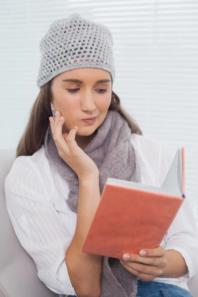 Thoughtful brunette with winter hat on holding notebook — Stock Photo, Image