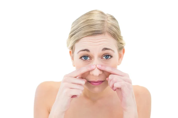 Frowning young blonde woman touching her nose — Stock Photo, Image