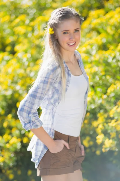 Donna con fiore nei capelli e mani nei pantaloni — Foto Stock