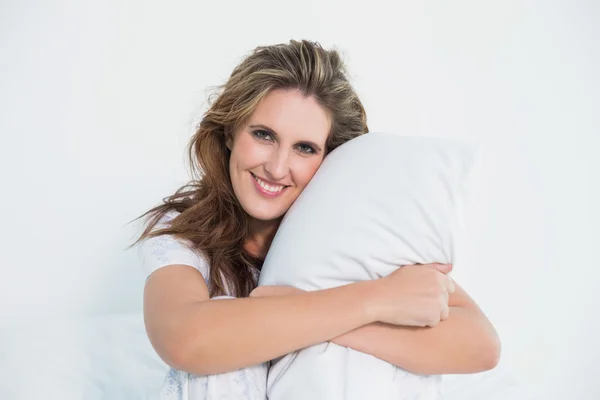 Smiling woman embracing pillow — Stock Photo, Image