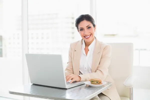 Glückliche Geschäftsfrau beim Mittagessen, während sie arbeitet — Stockfoto