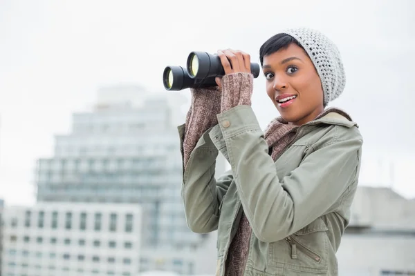 Amazed young model in winter clothes holding binoculars — Stock Photo, Image