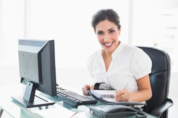 Gelukkig zakenvrouw in haar dagboek op haar Bureau schikken — Stockfoto