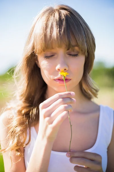 Mujer joven pensativa oliendo flor — Foto de Stock