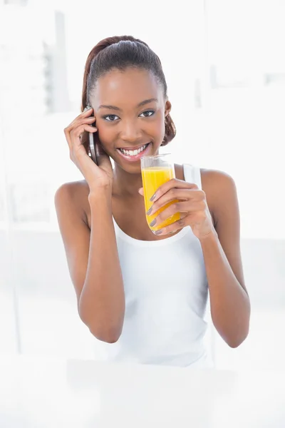 Feliz atlética mujer llamando mientras sostiene el jugo de naranja —  Fotos de Stock