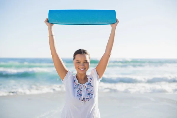 Lachende vrouw oefening mat houden over haar hoofd — Stockfoto