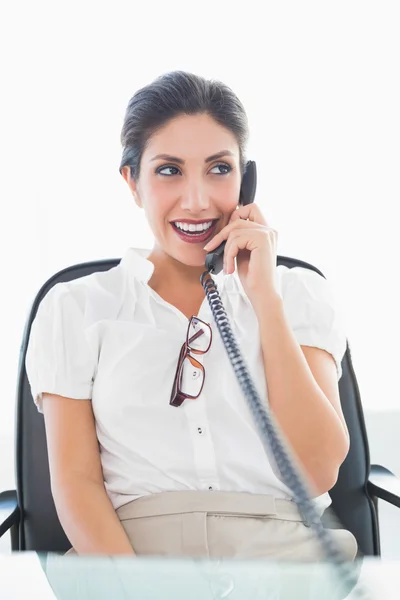 Empresária feliz sentada em sua mesa no telefone — Fotografia de Stock