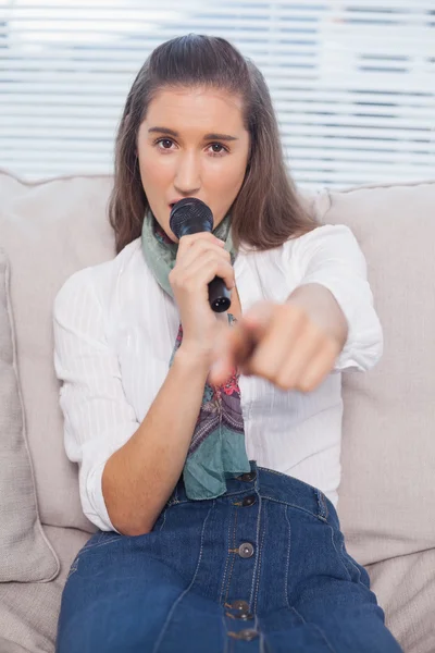 Preciosa modelo apuntando a la cámara cantando en el micrófono —  Fotos de Stock